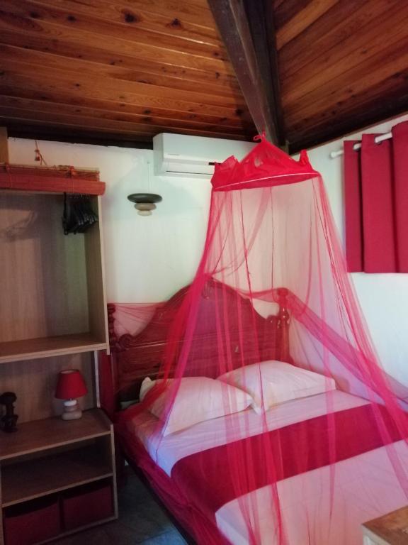 a bedroom with a bed with a red mosquito net at Cazadodo in Étang-Salé
