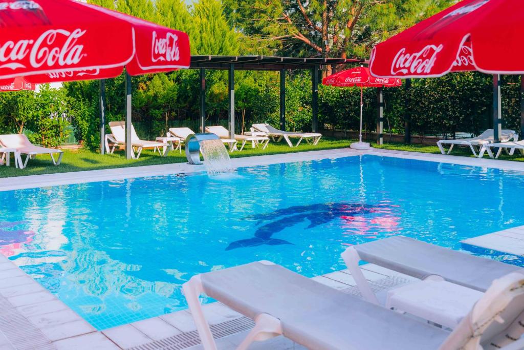 een zwembad met 2 cocacolaparasols en een zwembad bij Asil Apart Hotel in Burhaniye