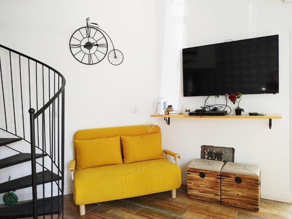 a living room with a yellow couch and a tv at Cohen's Jaffa Rooms in Tel Aviv