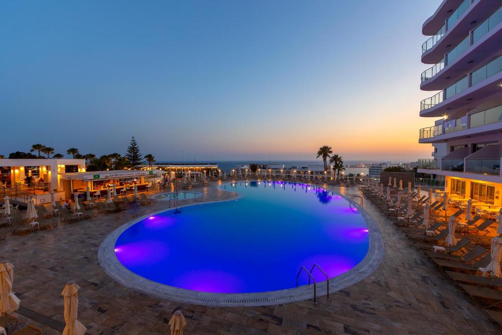 a large swimming pool with chairs and a building at Tofinis Hotel in Ayia Napa