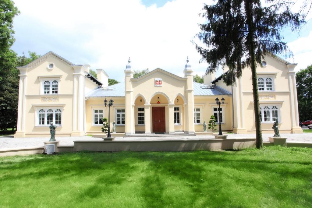 uma casa grande com um relvado verde em frente em Hotel Dwór Sójki em Sójki