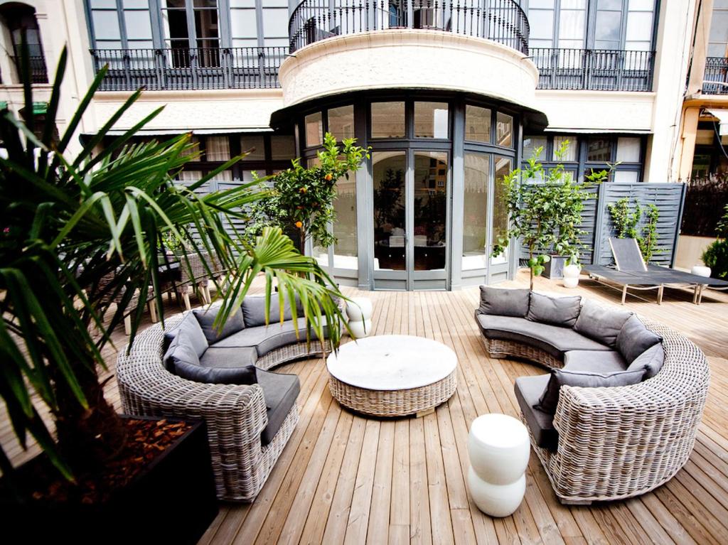 d'une terrasse avec des meubles en osier, une table et des chaises. dans l'établissement Praktik Rambla, à Barcelone