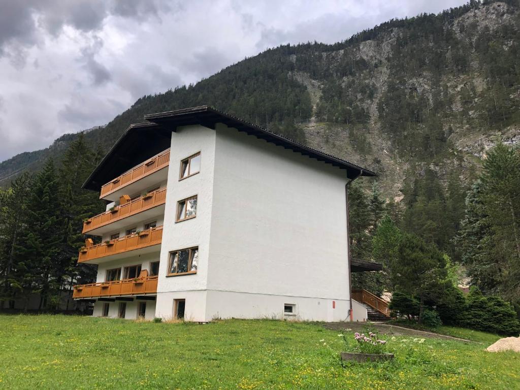 a building in a field next to a mountain at Karwendel-Lodge in Scharnitz