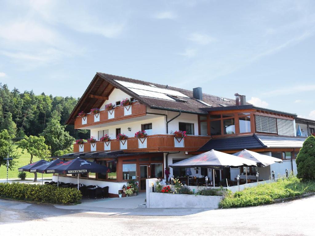 a large building with tables and umbrellas in front of it at Landgasthof Waldeck in Dürbheim