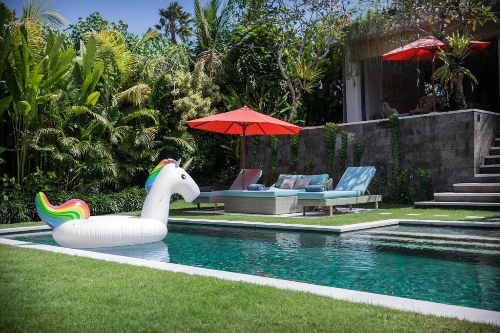 une piscine avec un flotteur de maïs gonflable dans une cour dans l'établissement Silversand Villa, à Tanah Lot