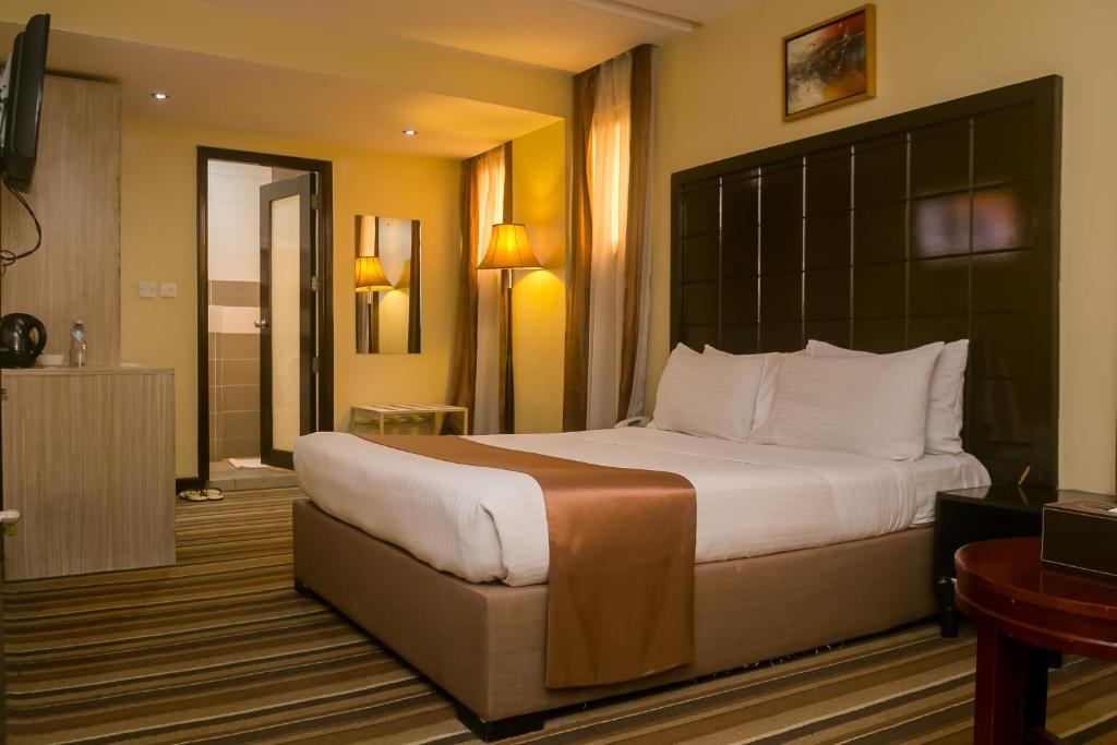 a hotel room with a bed and a dresser at The Clarion Hotel in Nairobi