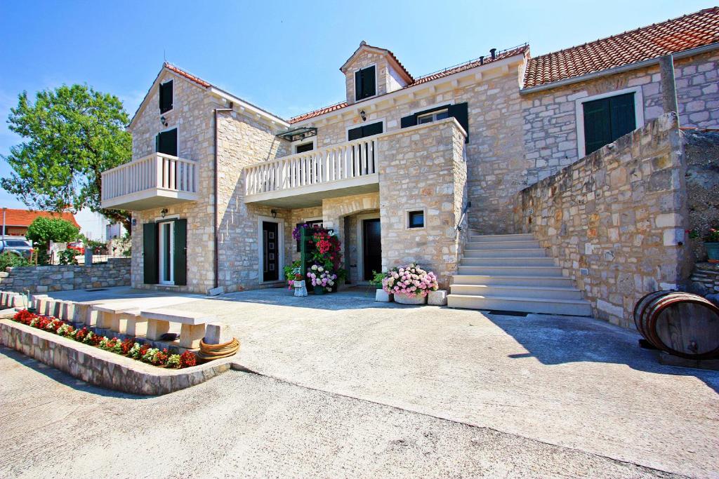 a large stone building with stairs and flowers in front of it at Apartment Igor in Supetar
