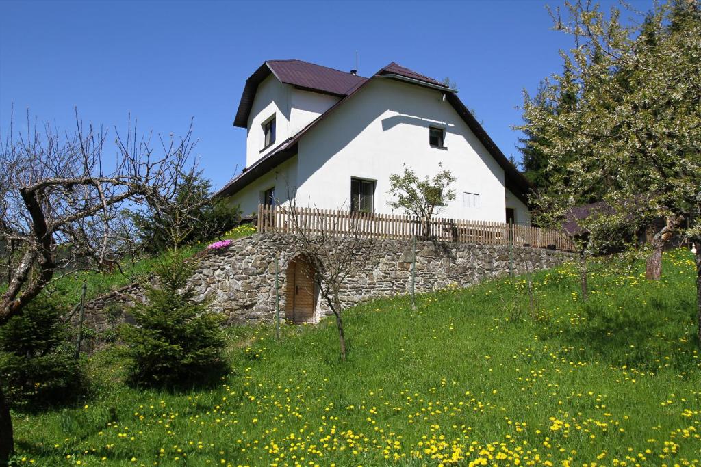 a white house on top of a stone wall at Penzion Na Kopečku in Velké Karlovice