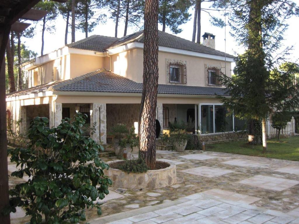 una casa grande con un árbol delante en El Chalet del Pinar, en Cuenca