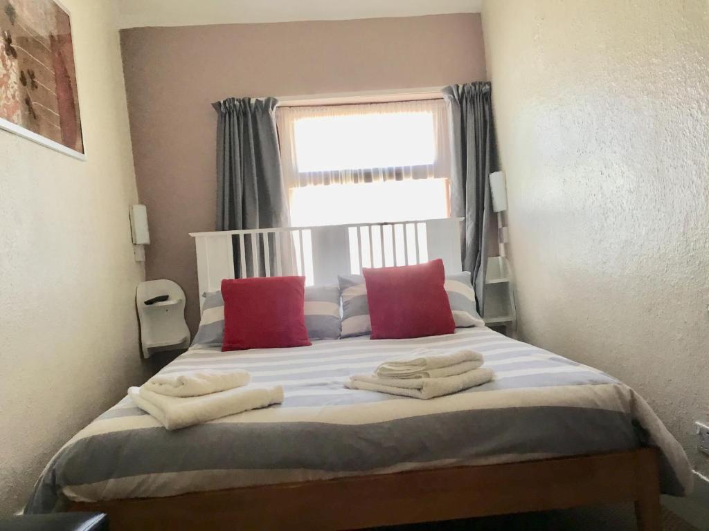 ブラックプールにあるKirkstall Guest Houseのベッドルーム1室(赤い枕のベッド1台、窓付)
