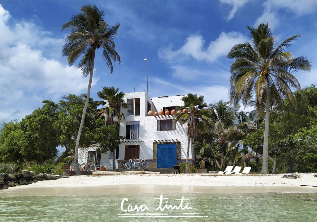 a white house on the beach with palm trees at Casa Tinti Hotel Boutique in Tintipan Island