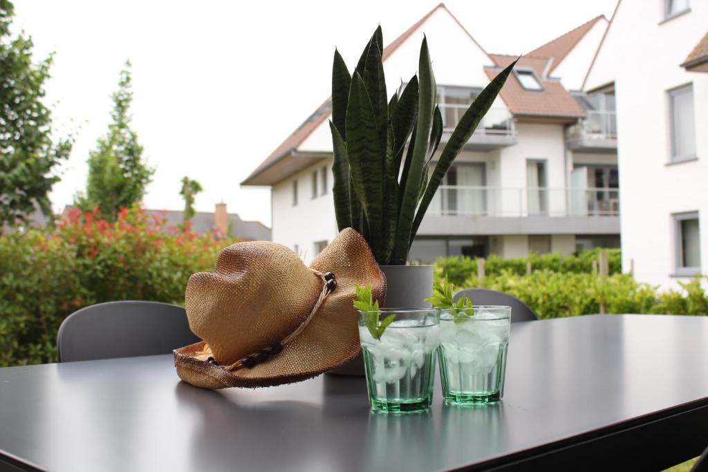 a hat sitting on a table with two glasses at Villa Appartement Amaryllis in Nieuwpoort