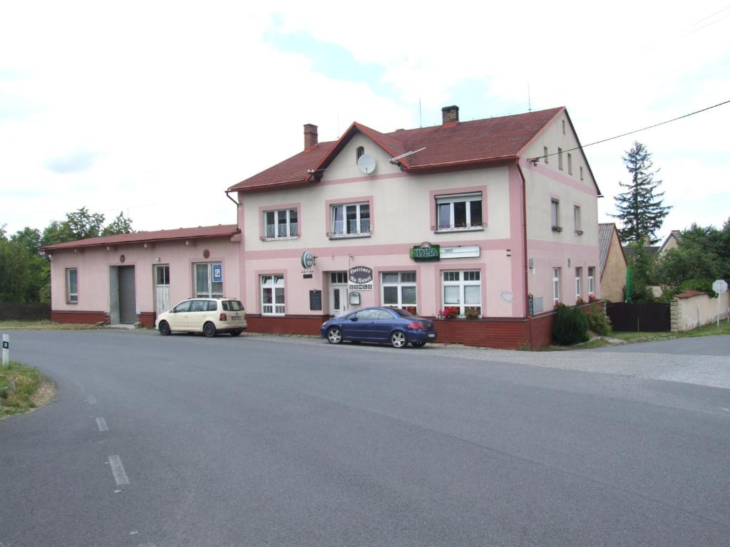een roze huis met twee auto's er voor geparkeerd bij Hostinec Na Návsi in Javorník