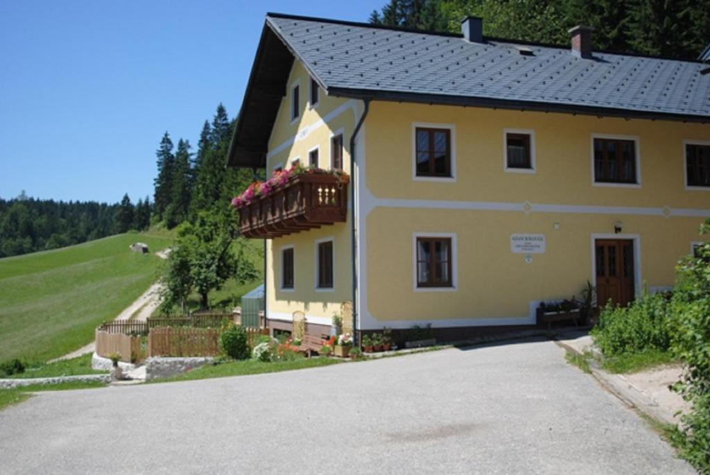 ein gelbes Haus mit einem Balkon und einer Einfahrt in der Unterkunft Familienbauernhof Glockriegl in Lunz am See