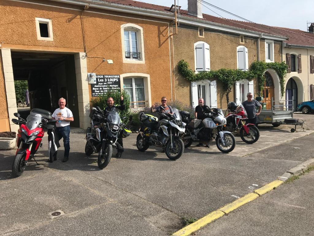een groep mensen op motorfietsen geparkeerd buiten een gebouw bij Aux 3 Loups in Châtenois