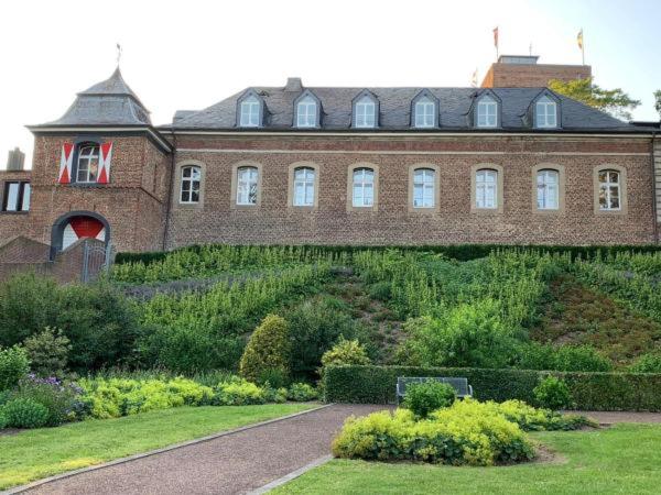 un grande edificio in mattoni con un giardino di fronte di Burg Wassenberg a Wassenberg