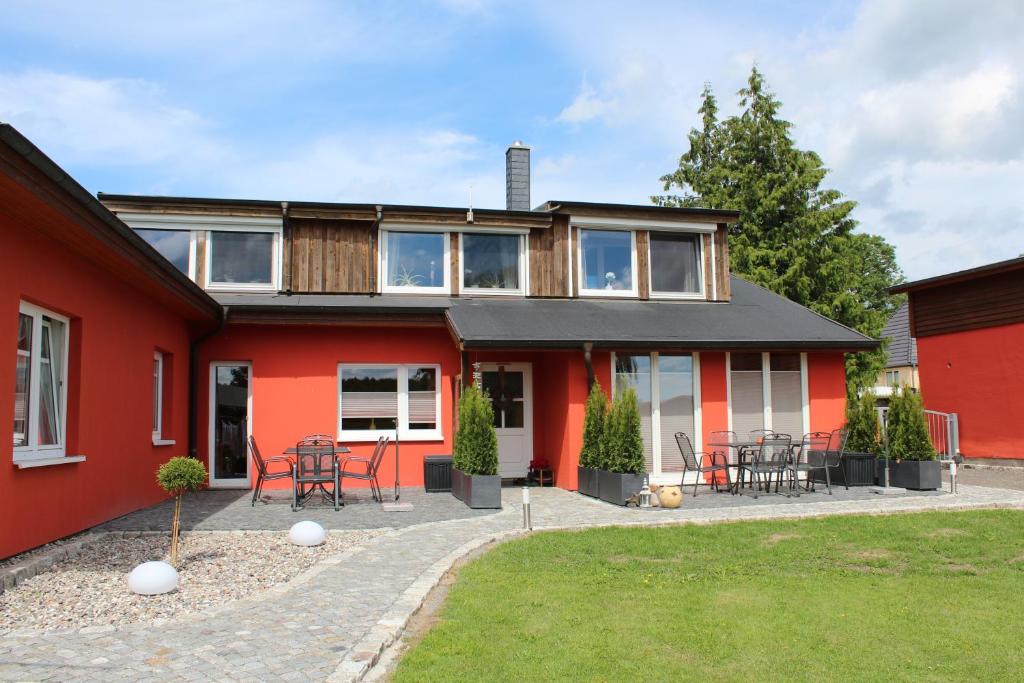a red house with a patio with tables and chairs at Naturcamp Duvendiek FeWo in Duvendiek