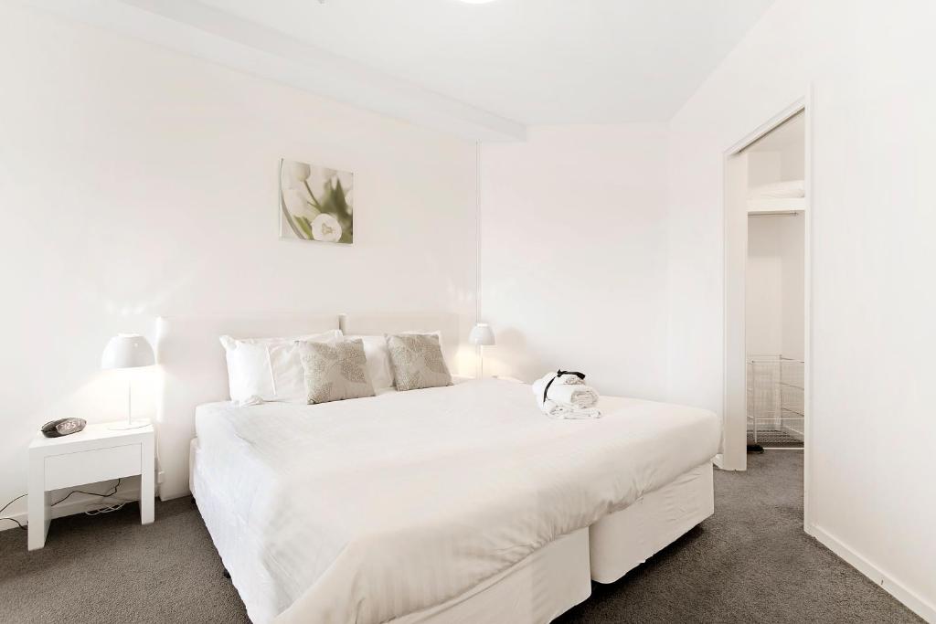 a white bedroom with a large white bed with white sheets at Docklands Private Collection - NEWQUAY in Melbourne