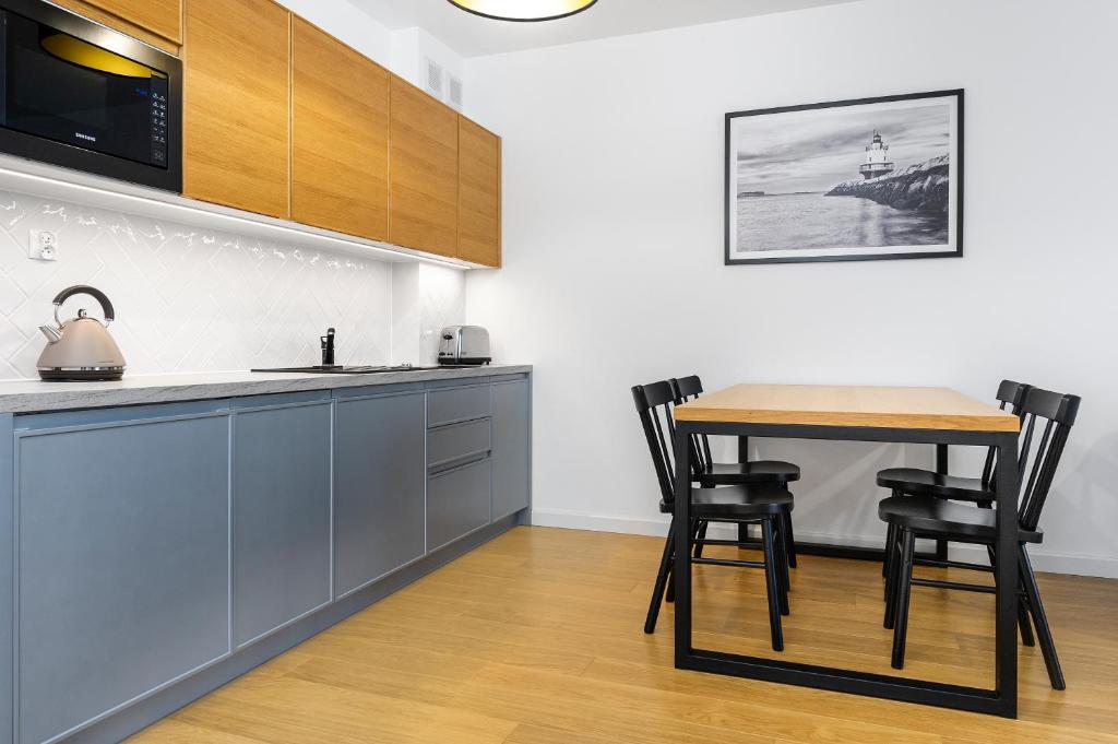 a kitchen with a table and chairs in a room at FARO Apartamenty Bliżej Morza in Kołobrzeg