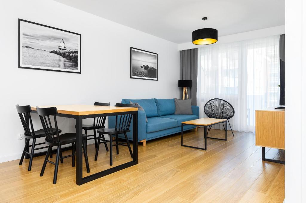 a living room with a blue couch and a table at FARO Apartamenty Bliżej Morza in Kołobrzeg