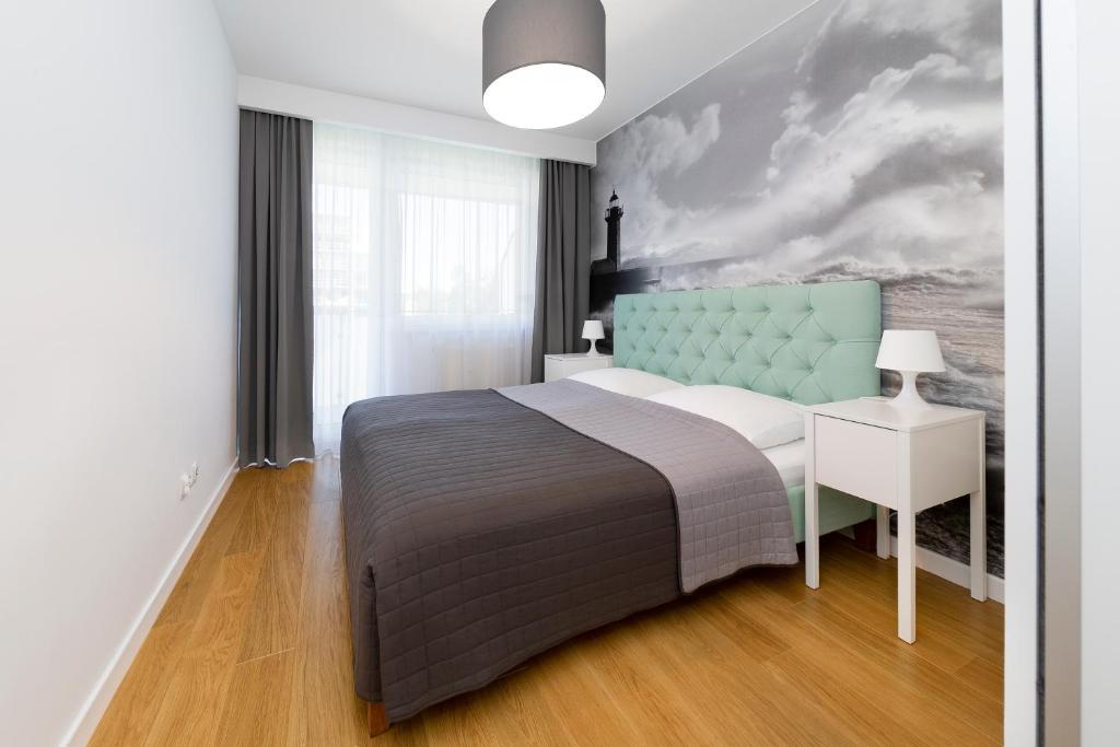 a bedroom with a bed and a painting on the wall at FARO Apartamenty Bliżej Morza in Kołobrzeg