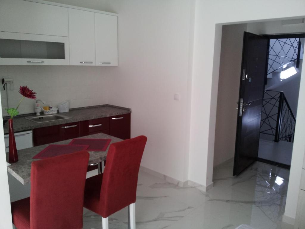 a kitchen with a table and two red chairs at Apartmani MITIĆ in Veliko Gradište