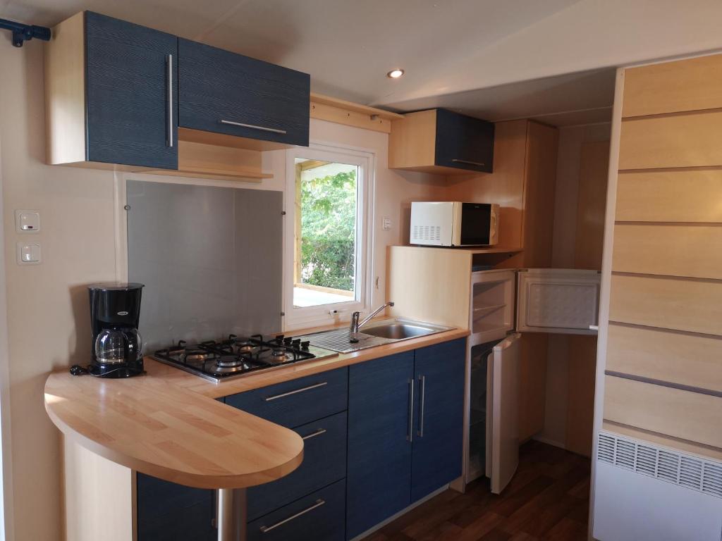 eine kleine Küche mit blauen Schränken und einem Waschbecken in der Unterkunft Mobil home climatisé en Alsace in Biesheim