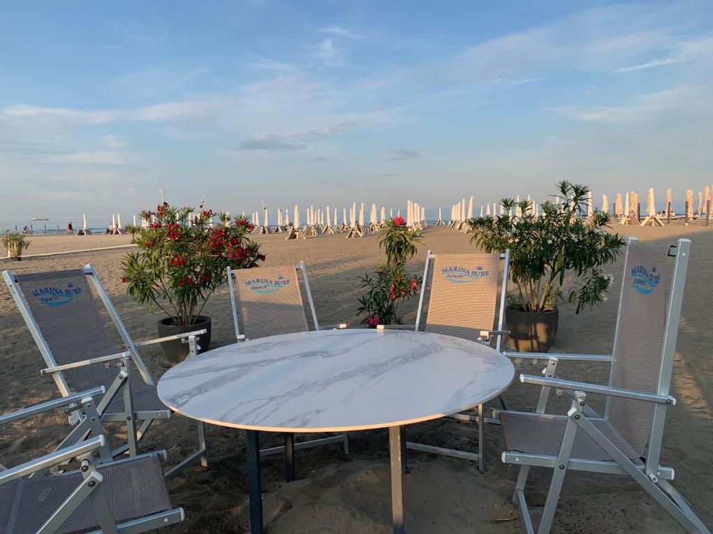 uma mesa branca e cadeiras na praia em Vela Luxury Sea View Apartments - Marina Surf em Mamaia Nord – Năvodari