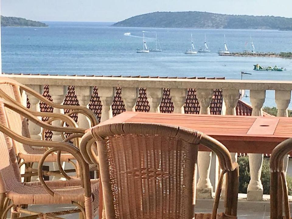 a wooden table and chairs on a balcony overlooking the water at Apartmani Nina in Šibenik