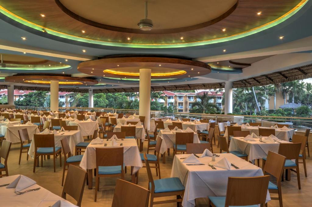 un ristorante con tavoli e sedie bianchi in una stanza di Viva Dominicus Palace by Wyndham, A Trademark All Inclusive a Bayahibe