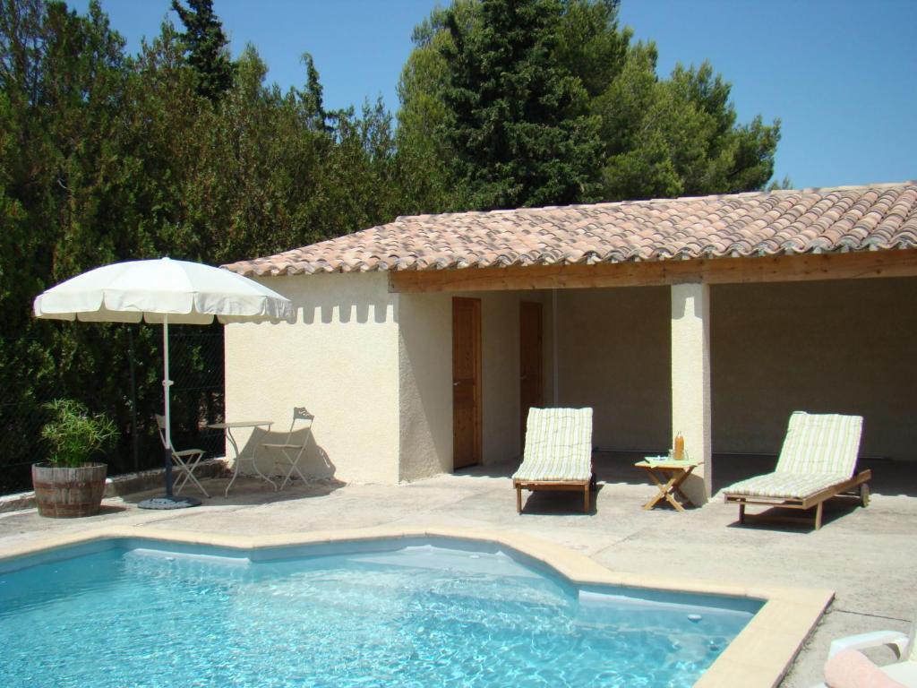 a swimming pool with two chairs and an umbrella at B&B L'Oustalet de Sylvie in Villeneuve-lès-Avignon