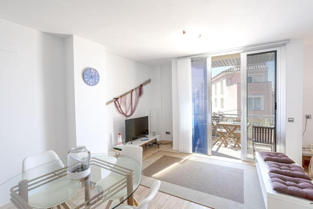 - un salon blanc avec une table en verre et des chaises blanches dans l'établissement Apartamento Nicol, à Pollença