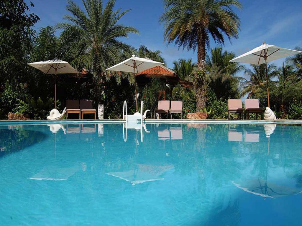 a large swimming pool with chairs and umbrellas at Rachavadee Bankrut Resort in Ban Krut
