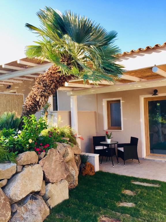 a house with a palm tree and a stone wall at Acquamaris Tuerredda in Teulada