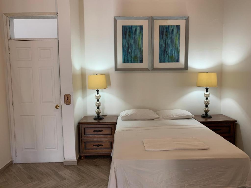 a bedroom with a bed and two lamps and a door at Palmira Hostel in Tegucigalpa