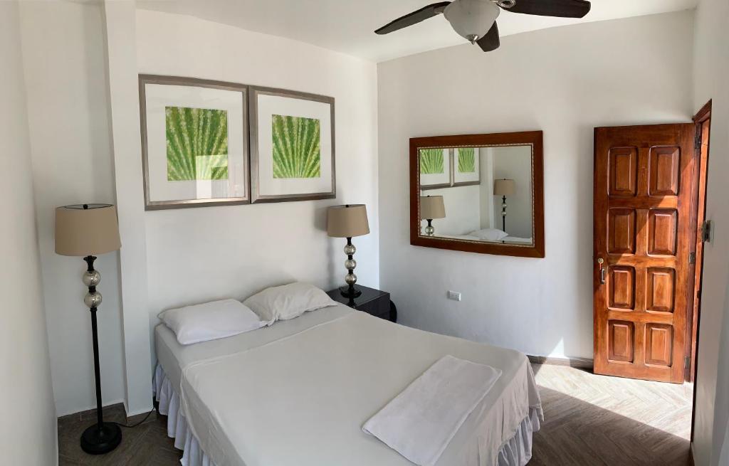 a bedroom with a bed and a ceiling fan and a mirror at Palmira Hostel in Tegucigalpa