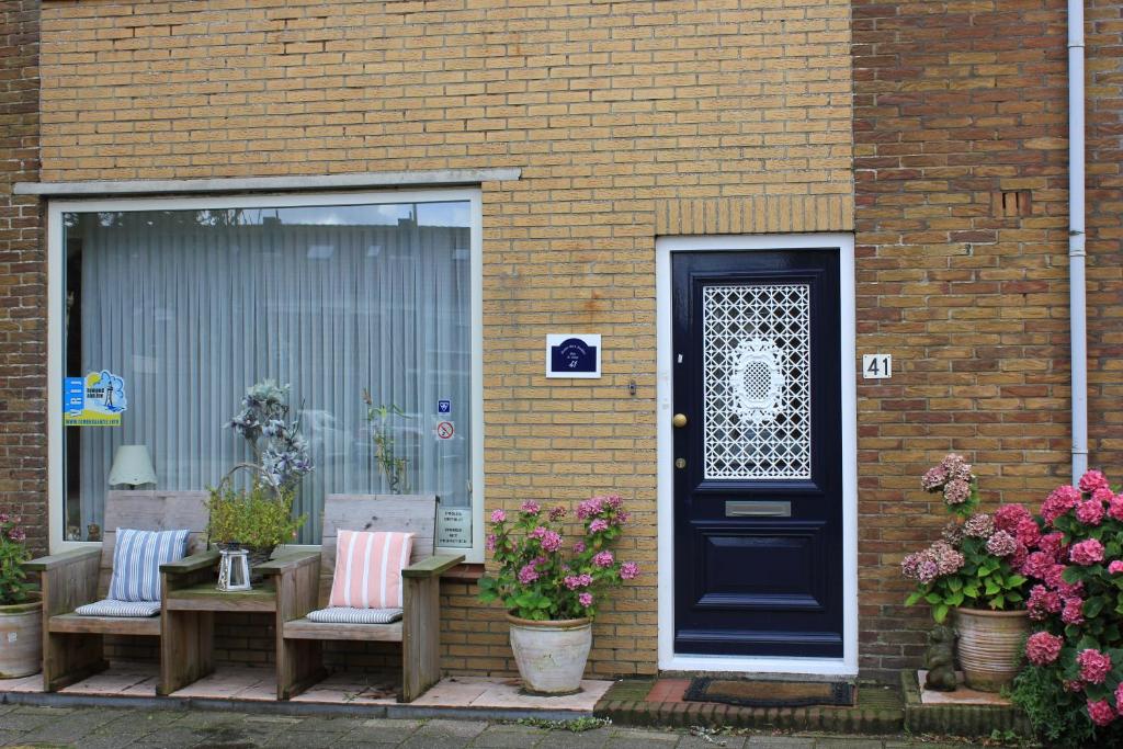 una casa con una puerta azul y dos sillas y flores en Kerstins Bed and Breakfast, en Egmond aan Zee