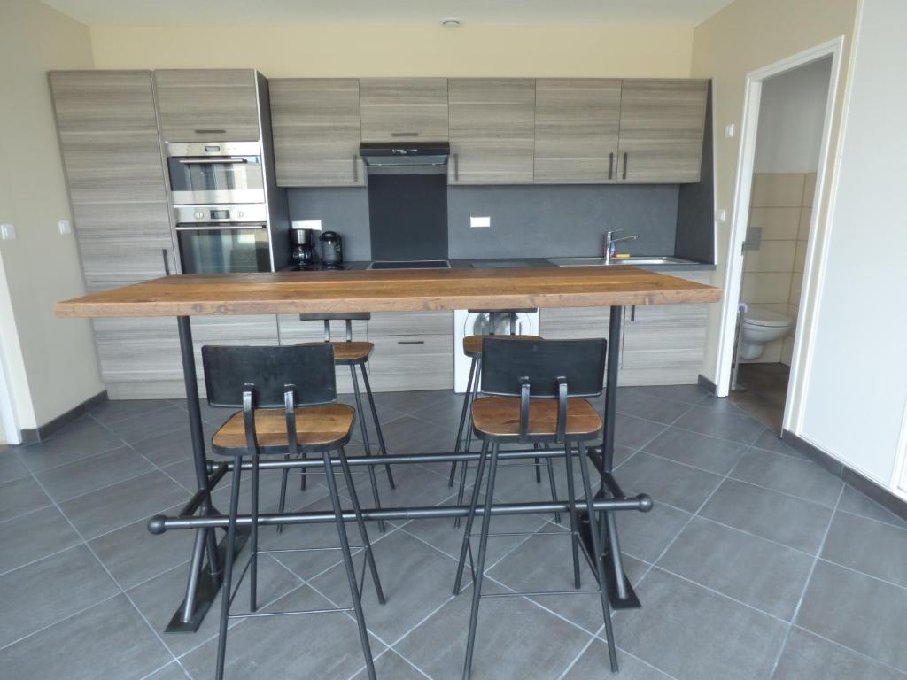 a kitchen with a counter with three bar stools at Appartement Plein Sud in Berck-sur-Mer