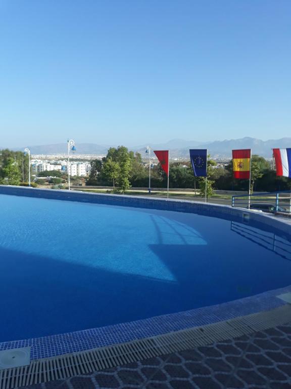 a large blue swimming pool with flags in the background at Appart-Hotel Cabo Dream in Cabo Negro
