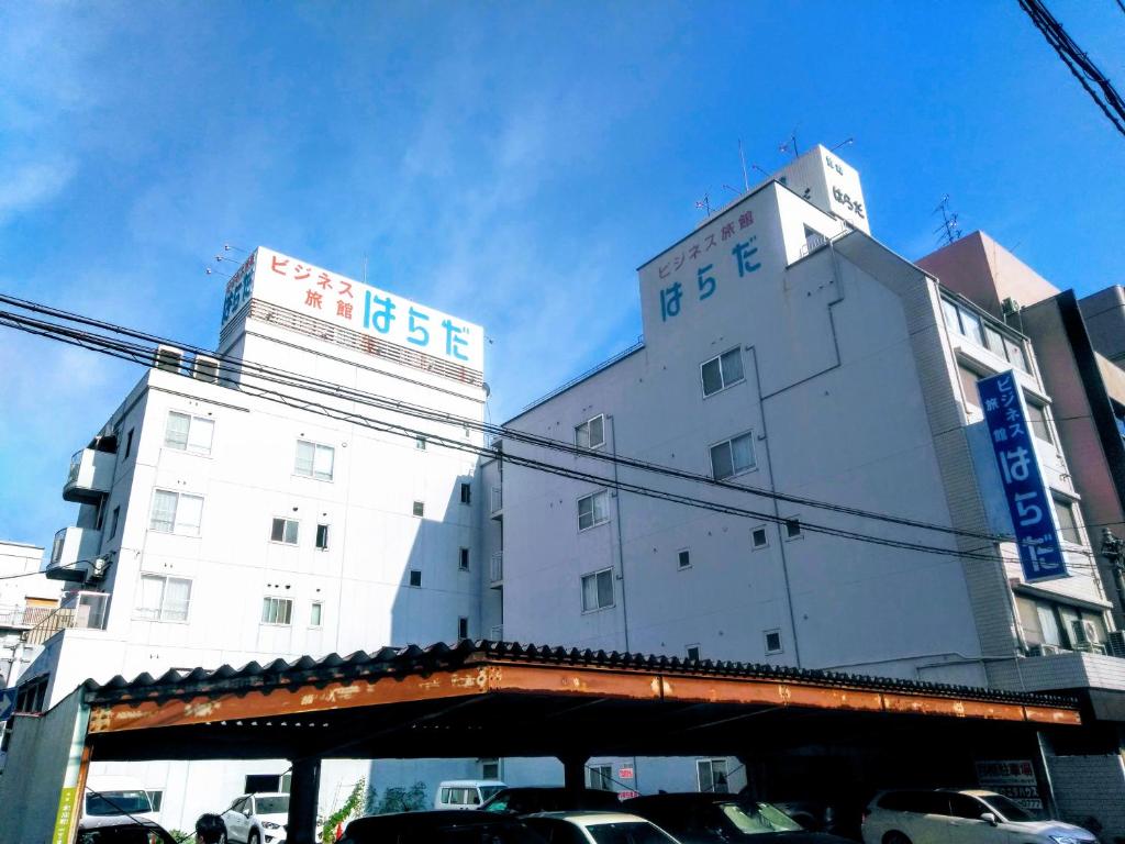 un grand bâtiment blanc avec des voitures garées devant lui dans l'établissement Business Ryokan Harada, à Hiroshima