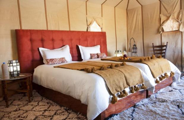 a bedroom with a large bed with a red headboard at Maroc Sahara Luxury Camp & Tours in Foum Zguid