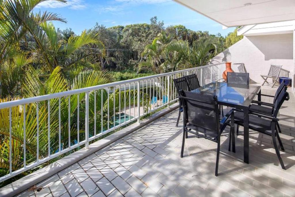 a patio with a table and chairs on a balcony at Kendall Beach Apartments 5 - Belongil Beach in Byron Bay