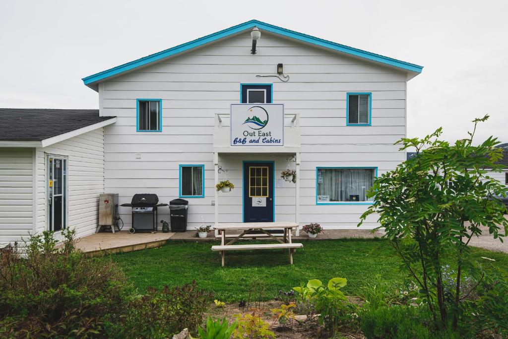 a white building with a picnic table in front of it at Out East B&B in Norris Point