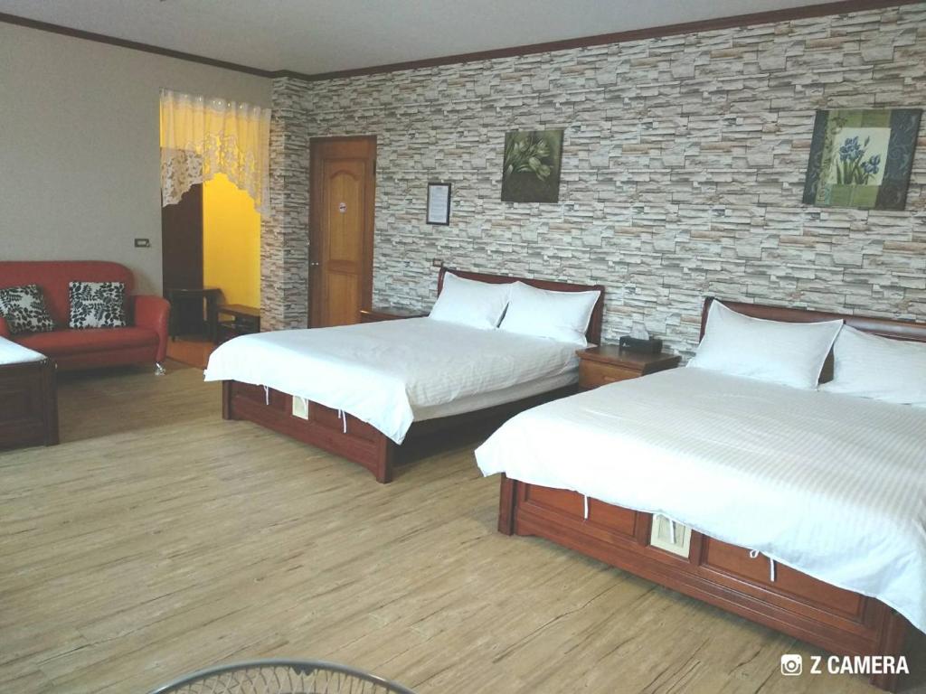 een slaapkamer met 2 bedden en een bakstenen muur bij Ju Jia Xiao Zhan Homestay in Guanshan