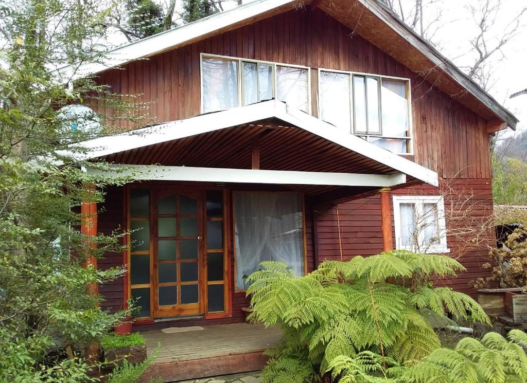 una pequeña casa de madera con una puerta grande en Casa cabaña, en Curarrehue