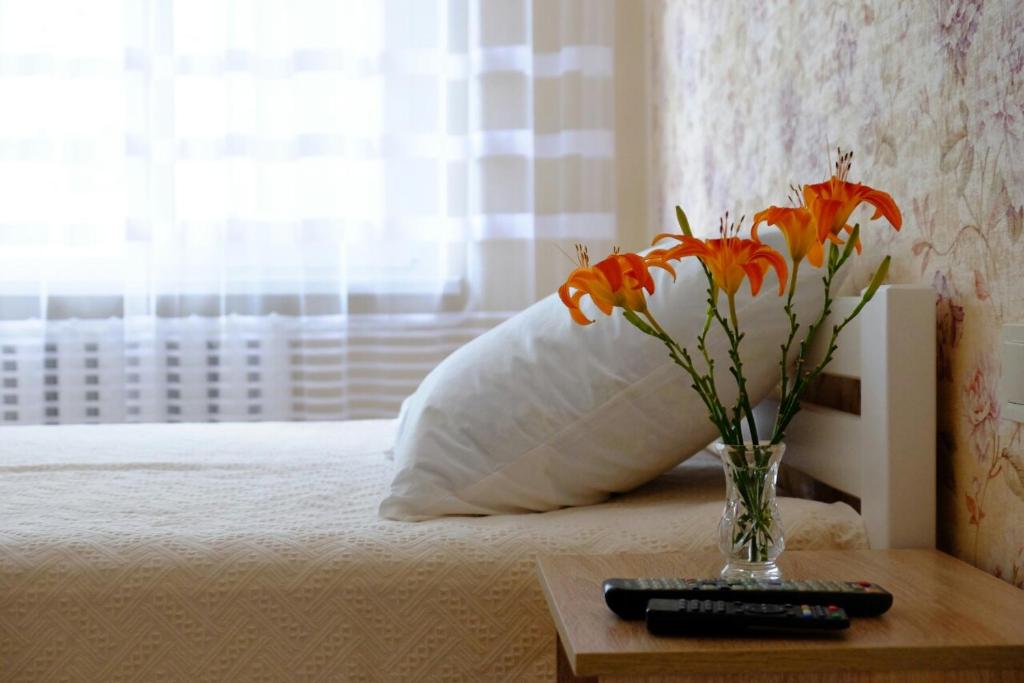 a vase of flowers on a table next to a bed at Квартира у моря на Фонтане Аркадия Одесса in Odesa