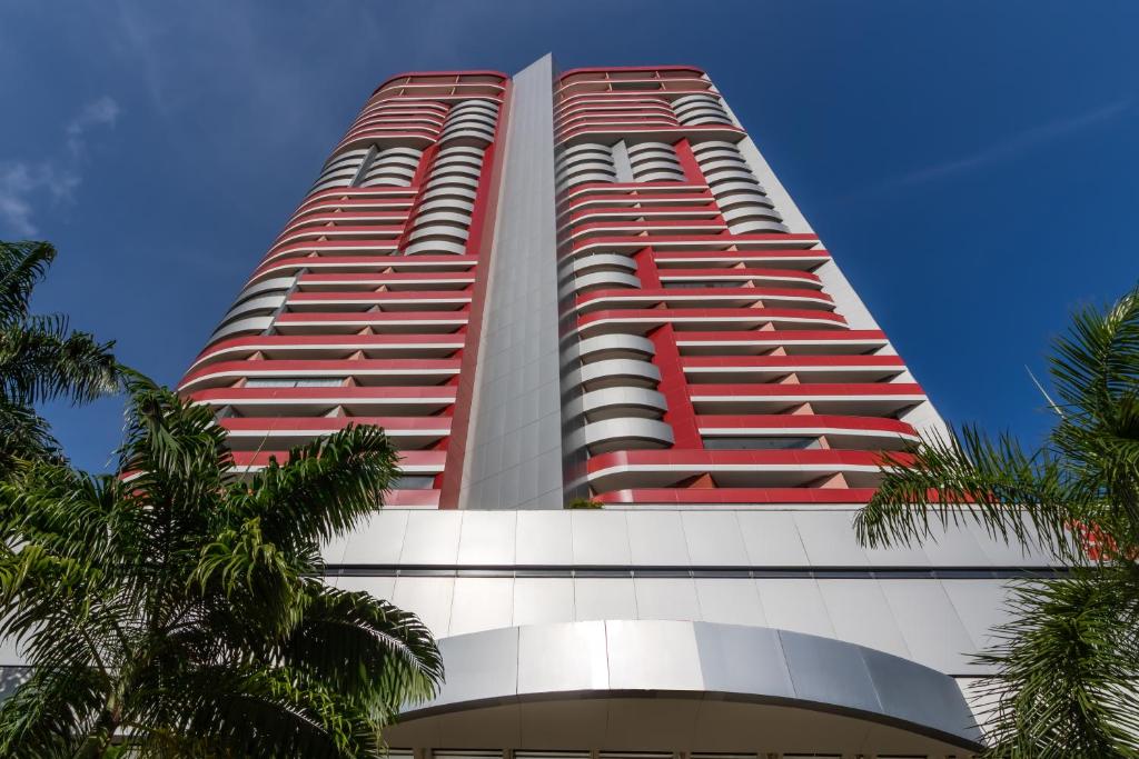 a tall red building with palm trees in front of it at Boulevard Residencial in Salvador