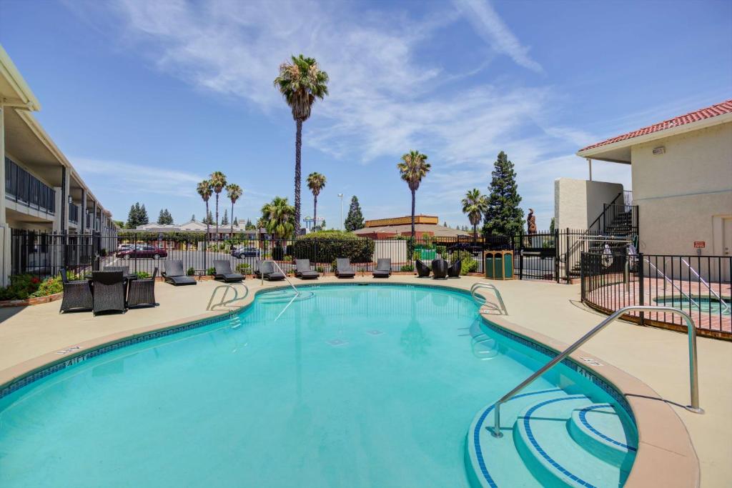 a large swimming pool with chairs and palm trees at Best Western Sandman Hotel in Sacramento
