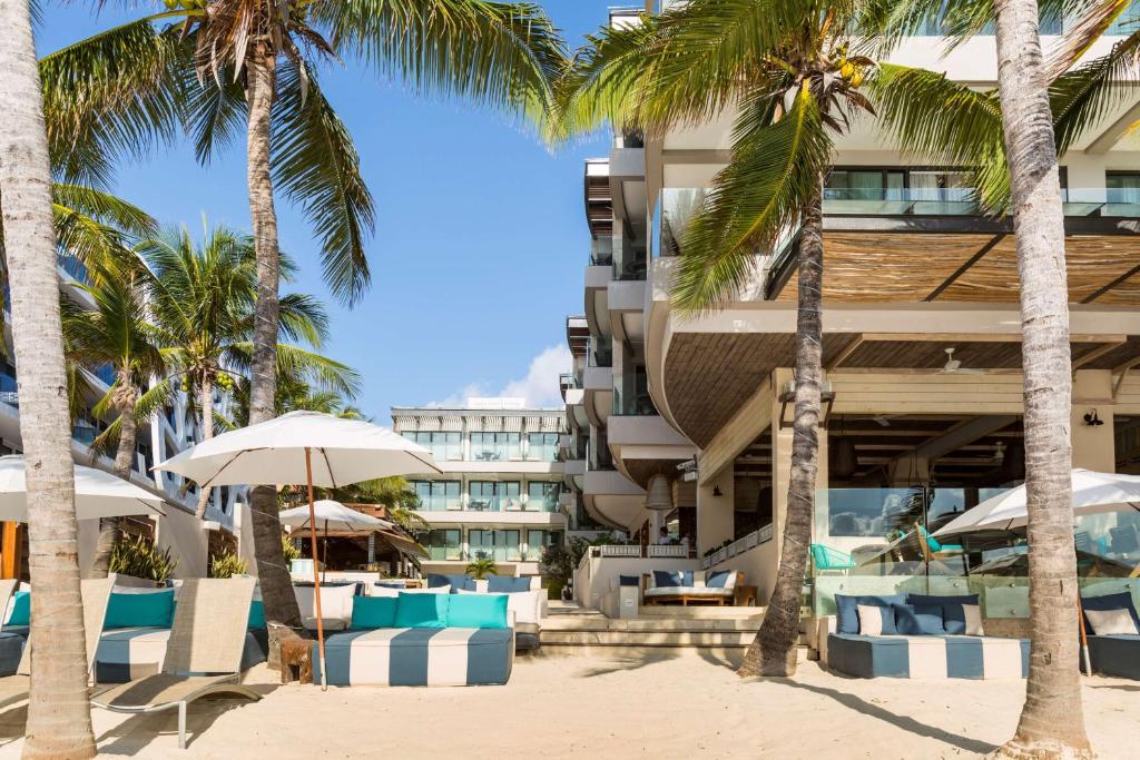 a hotel on the beach with palm trees and umbrellas at Thompson Playa del Carmen Beach House, part of Hyatt in Playa del Carmen