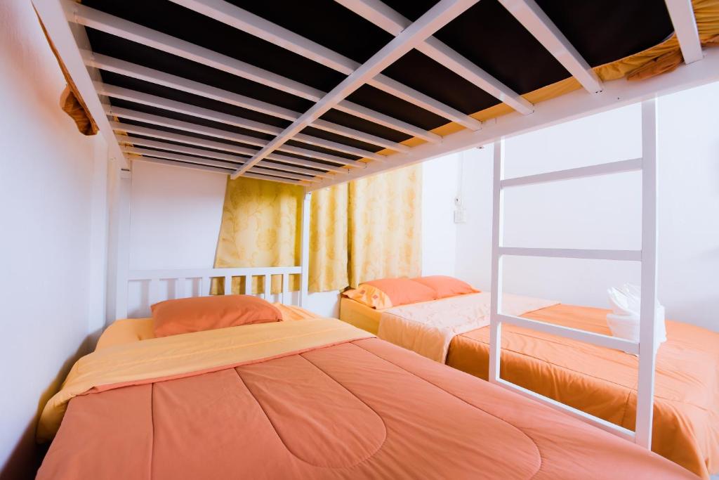 two beds in a room with orange sheets at Nadpob Mansion in Surat Thani